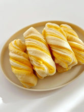 Three twisted bread loaves on a beige plate with a white background