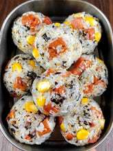 Bowl of rice balls with salmon and corn on a wooden surface