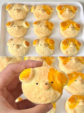 Pig-shaped pastries on a tray with a hand holding one