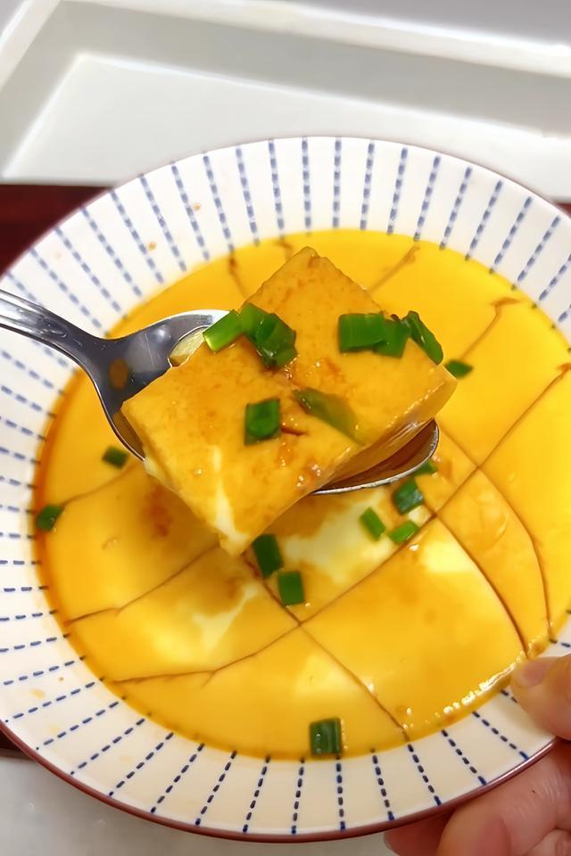 Steamed egg dish with green onions on a plate with a fork