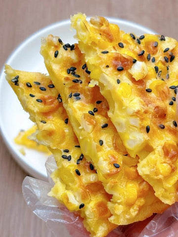Corn pancakes with black sesame seeds on a white plate