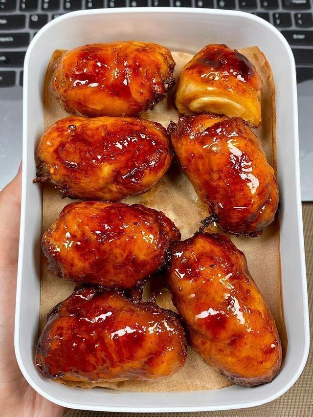 Glazed chicken wings in a white container on a wooden surface