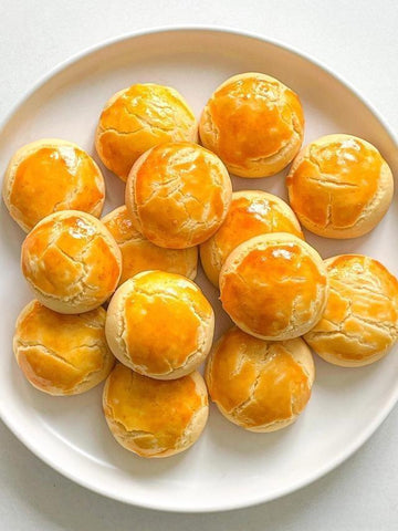 Plate of golden-brown pastries with a glossy finish on a white background