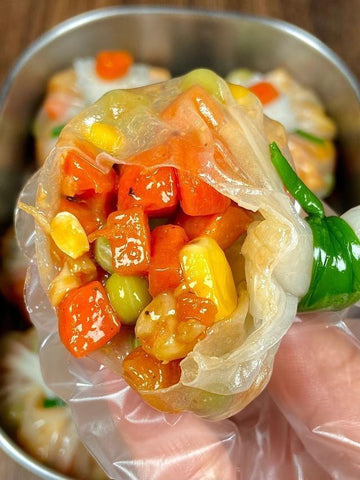 Close-up of a dumpling filled with colorful vegetables, held by a gloved hand.