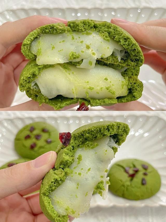 Green matcha cookie with white cream filling held by a hand, with another cookie in the background.